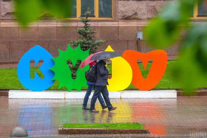 Люди з парасолями під дощем біля інсталяції «КИЇВ» у Києві 1 квітня