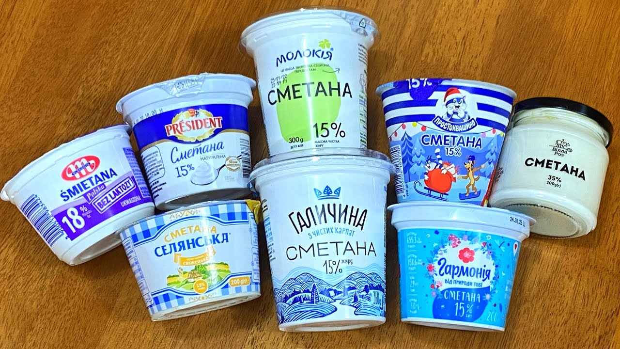Різні упаковки магазинної сметани 15% та 20% жирності на деревяному столі