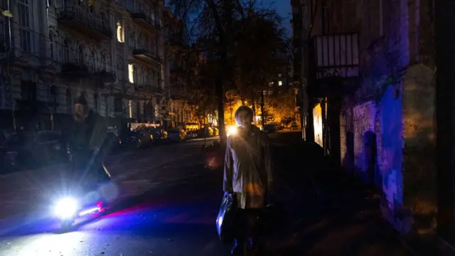 Темна вулиця Славутича без електроенергії вночі, жителі з ліхтарями та патрульною машиною