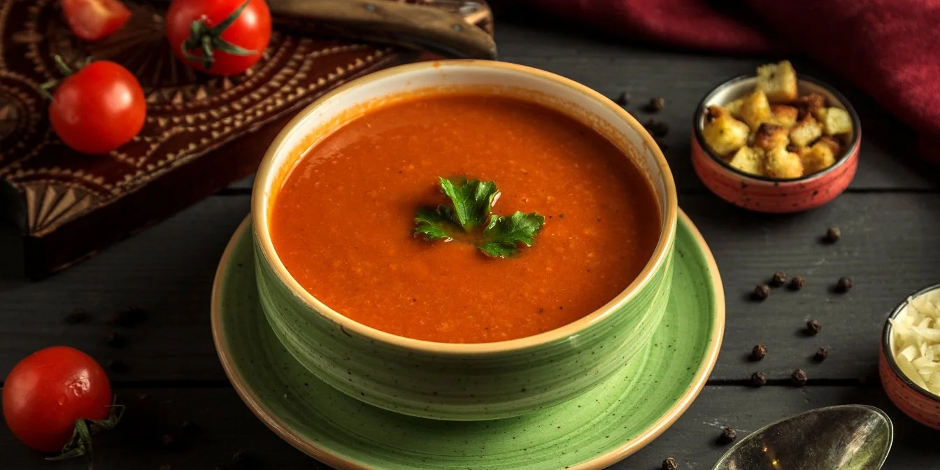 ТОП-3 самых вкусных томатных супов: шедевры из свежих овочей Томатный суп в зелёной миске с петрушкой, помидорами и хлебными кубиками