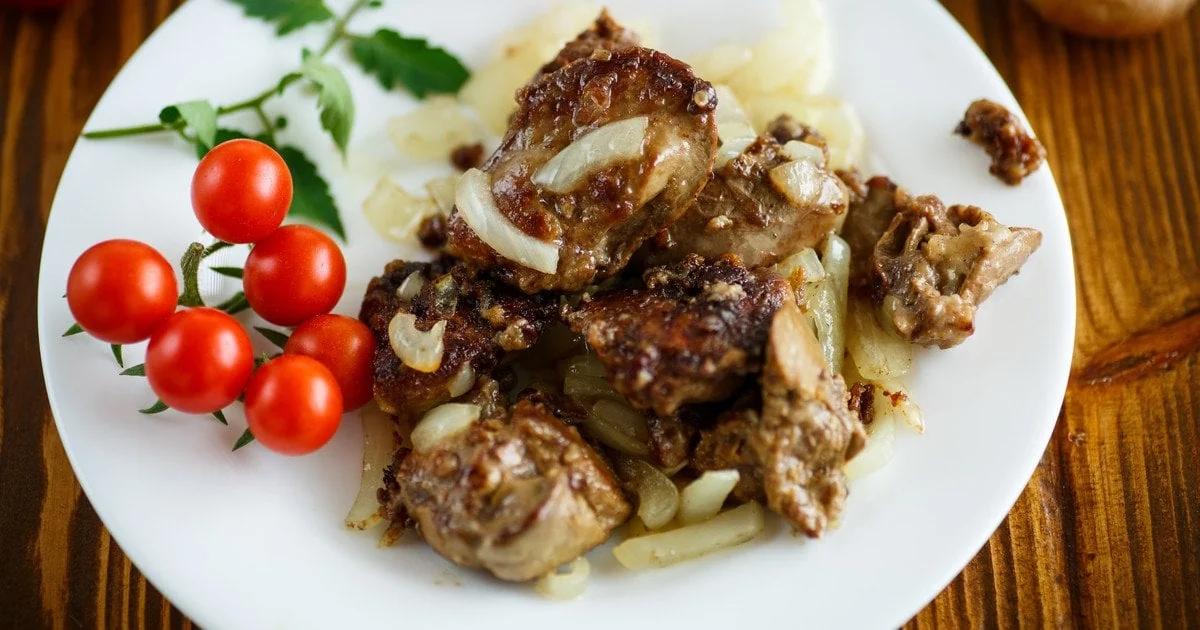 Щепотка соды: секрет нежной куриной печени, которая тает во рту Нежная куриная печенка с луком и помидорами черри на тарелке