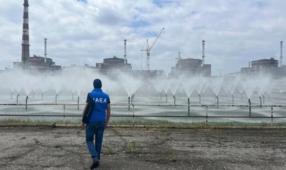 Представник МАГАТЕ йде вздовж огорожі Запорізької АЕС з реакторними блоками