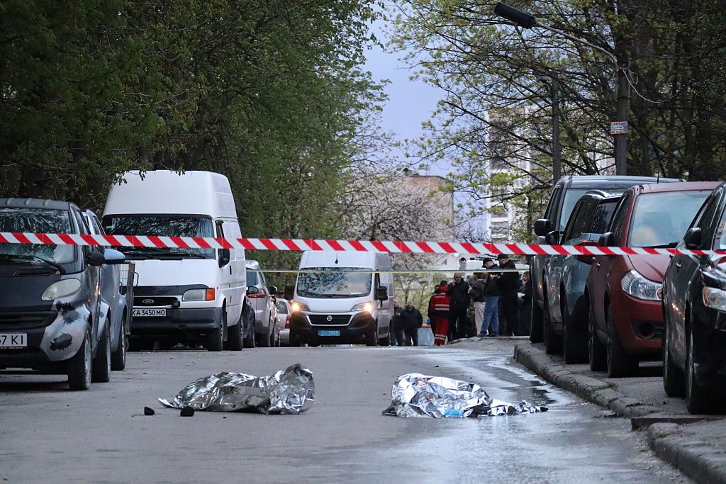 Поліцейські стрічки огороджують місце масової стрілянини в Києві з вкритими тілами