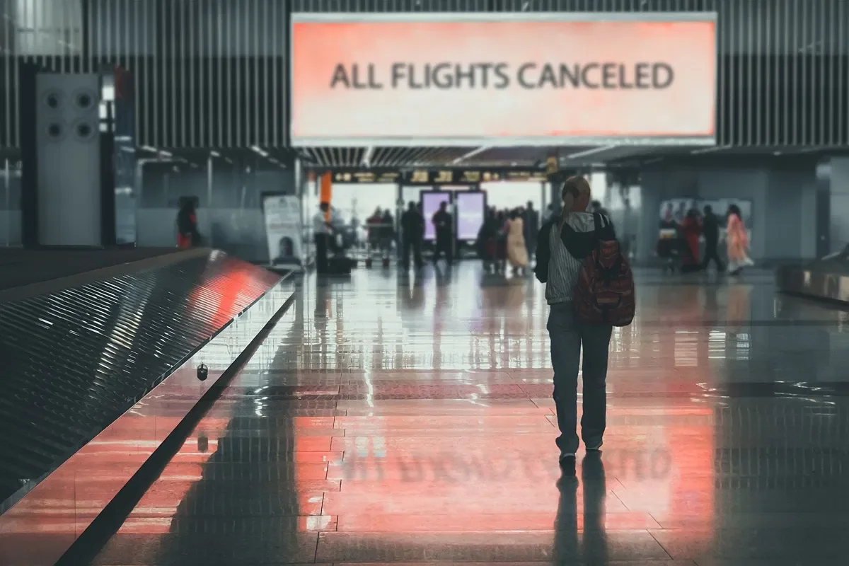 Розгублені пасажири в аеропорту перед табло «ALL FLIGHTS CANCELED» через скасування рейсів