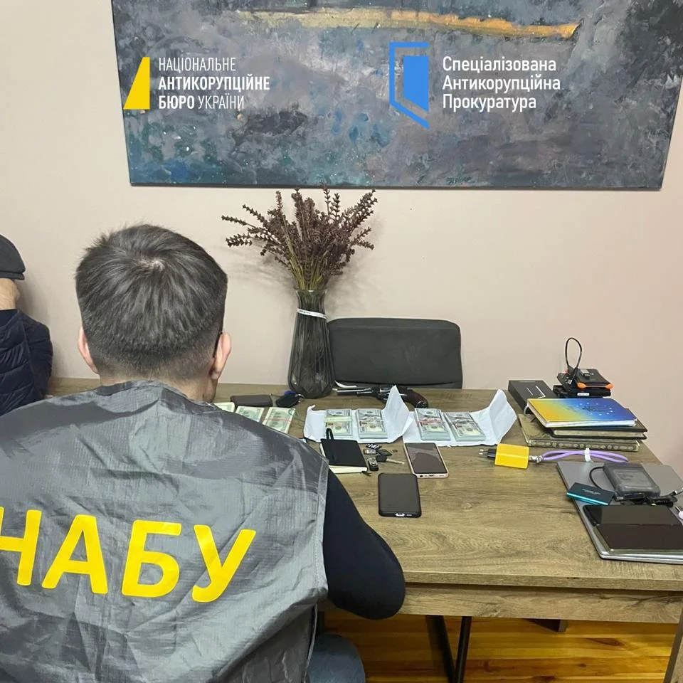 Детективи НАБУ оглядають пачки доларів на столі Полтавської обласної прокуратури під час обшуку