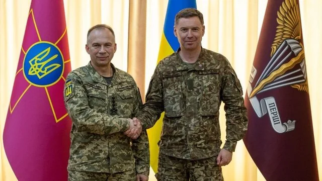 Олександр Сирський тисне руку військовому перед прапорами ЗСУ та ДШВ