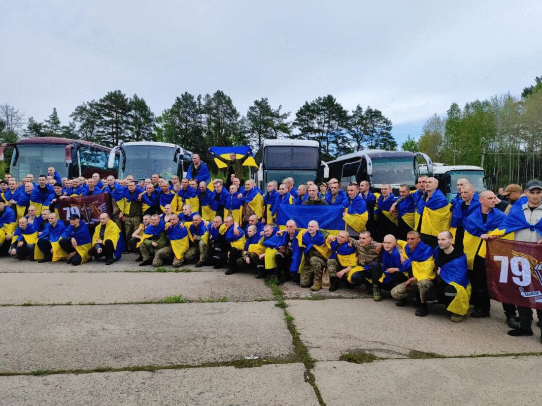 175 звільнених полонених у синьо-жовтих комбінезонах перед автобусами