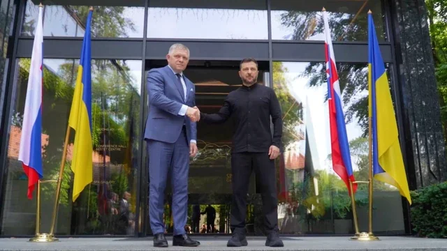 Роберт Фіцо та Володимир Зеленський потискають руки перед прапорами Словаччини й України