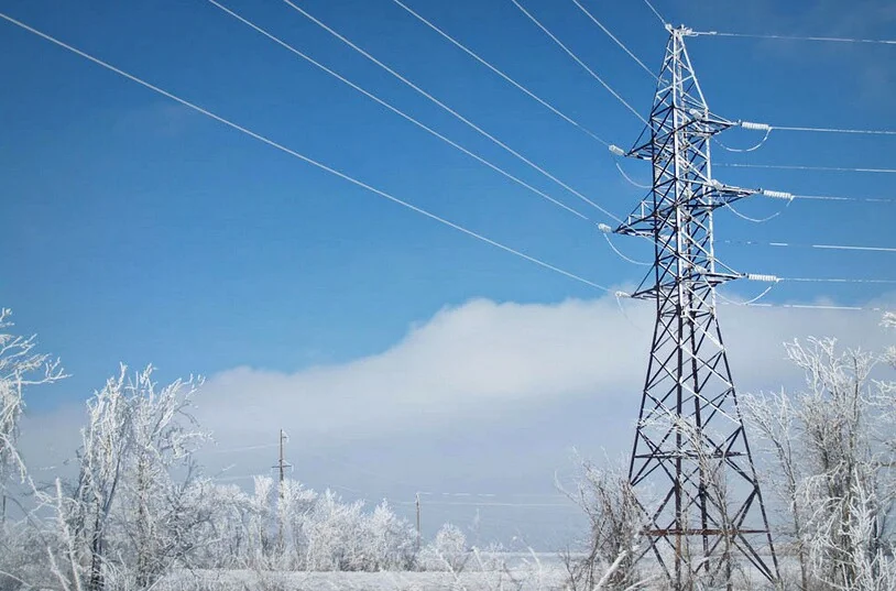 Опора ЛЕП у засніженому полі областей без світла через негоду