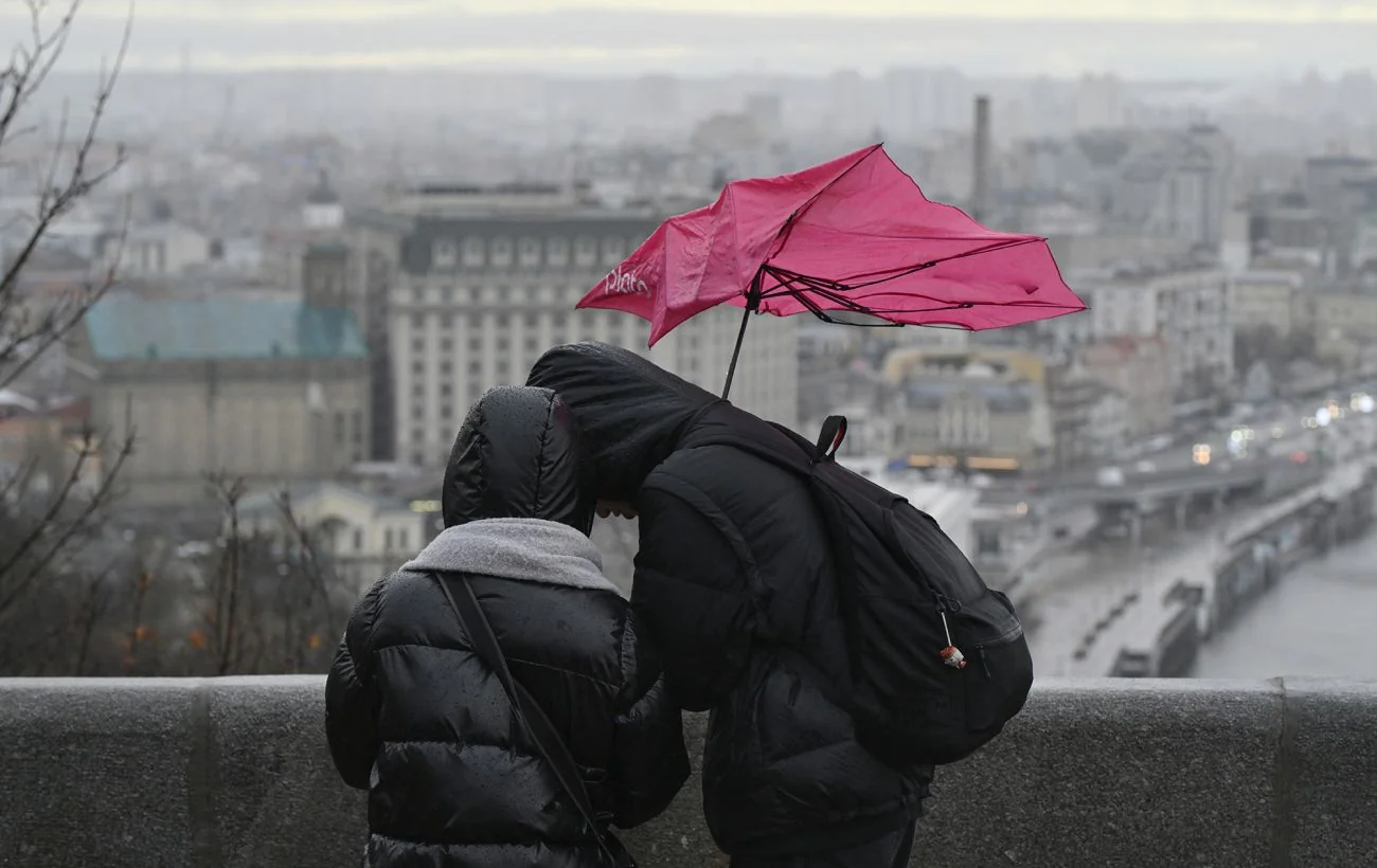 Люди з червоною парасолькою на сильному вітрі в Києві під час дощу 13 травня
