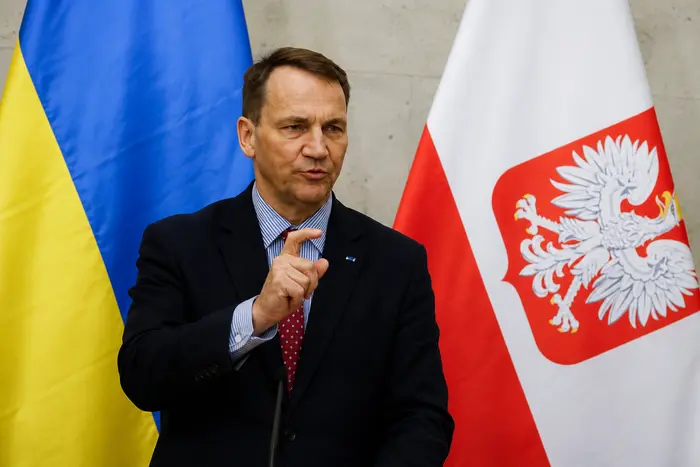 Радослав Сікорський виступає на тлі прапорів України та Польщі