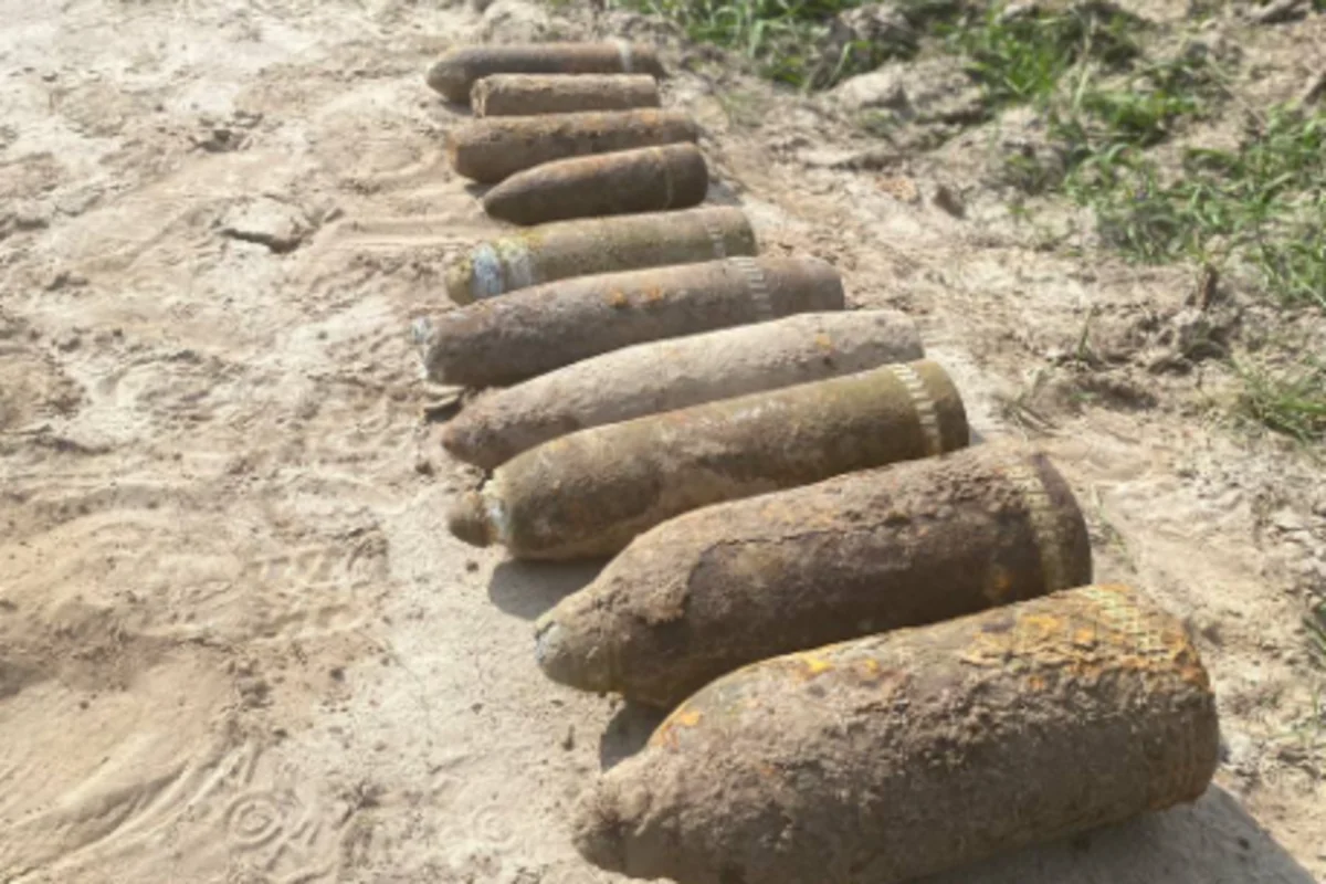 Ряд іржавих 203-мм снарядів Б-4 часів Другої світової на ґрунті