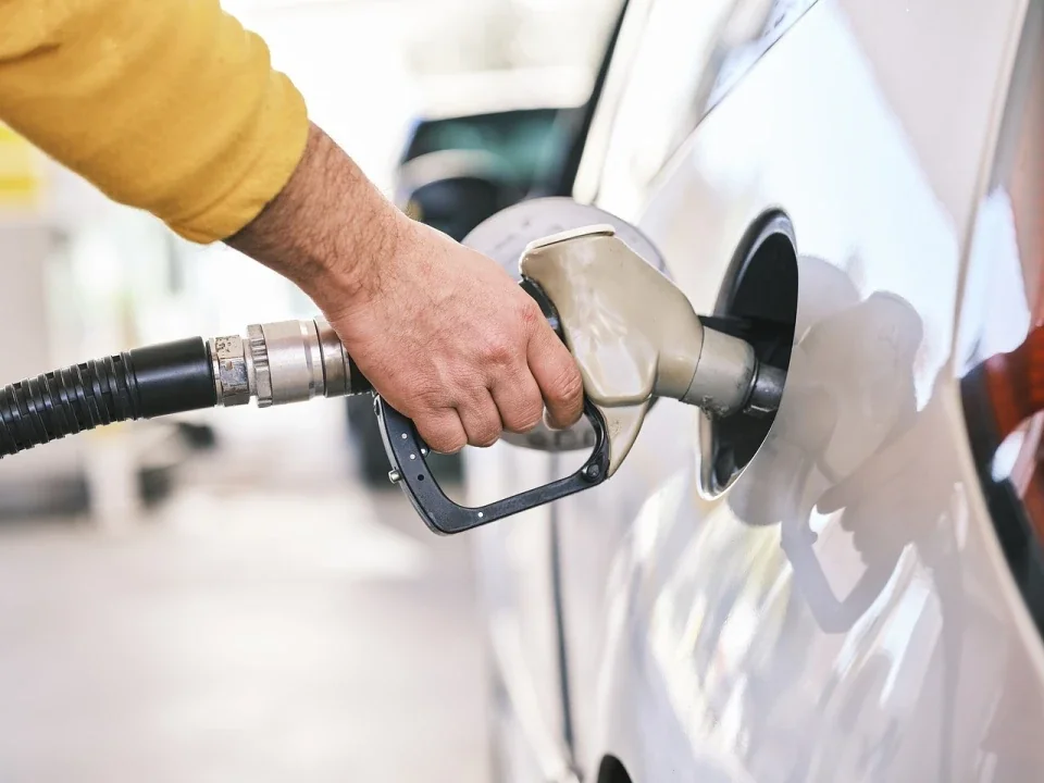 Рука заправляє бензином білий автомобіль на АЗС в Україні