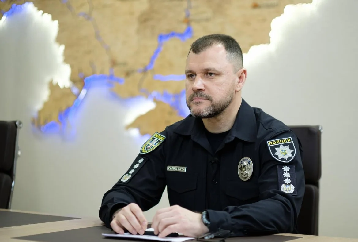 Ігор Клименко в формі поліції за столом на тлі карти України