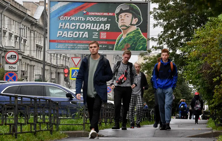 В Петербурге вербуют на ПВО: 2350 долларов в месяц без отправки на фронт Молодые мужчины проходят мимо билборда вербовки на службу в российскую армию в Санкт-Петербурге