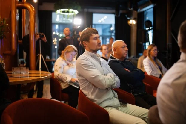Люди сидять у червоних кріслах у кафе під час заходу з камерами