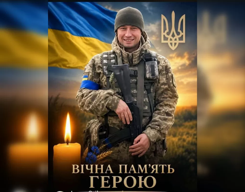 Усміхнений військовий у пікселі з автоматом на тлі прапора, тризуба і свічки