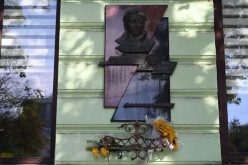 Меморіальна дошка з барельєфом Івана Гавдиди та жовтими квітами на фасаді будинку