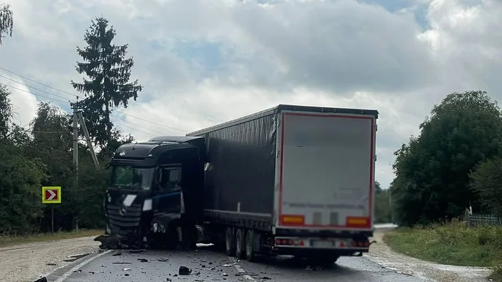 Пошкоджена чорна вантажівка Mercedes з причепом на сільській дорозі після зіткнення