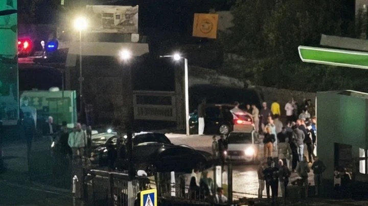 Нічне скупчення людей і авто біля АЗС під ліхтарями з поліцейськими вогнями