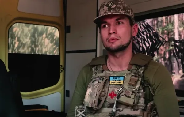 Бойовий медик у піксельній формі та розгрузці сидить у салоні військового авто