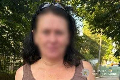 Жінка з розмитим обличчям у майці стоїть на вулиці серед дерев
